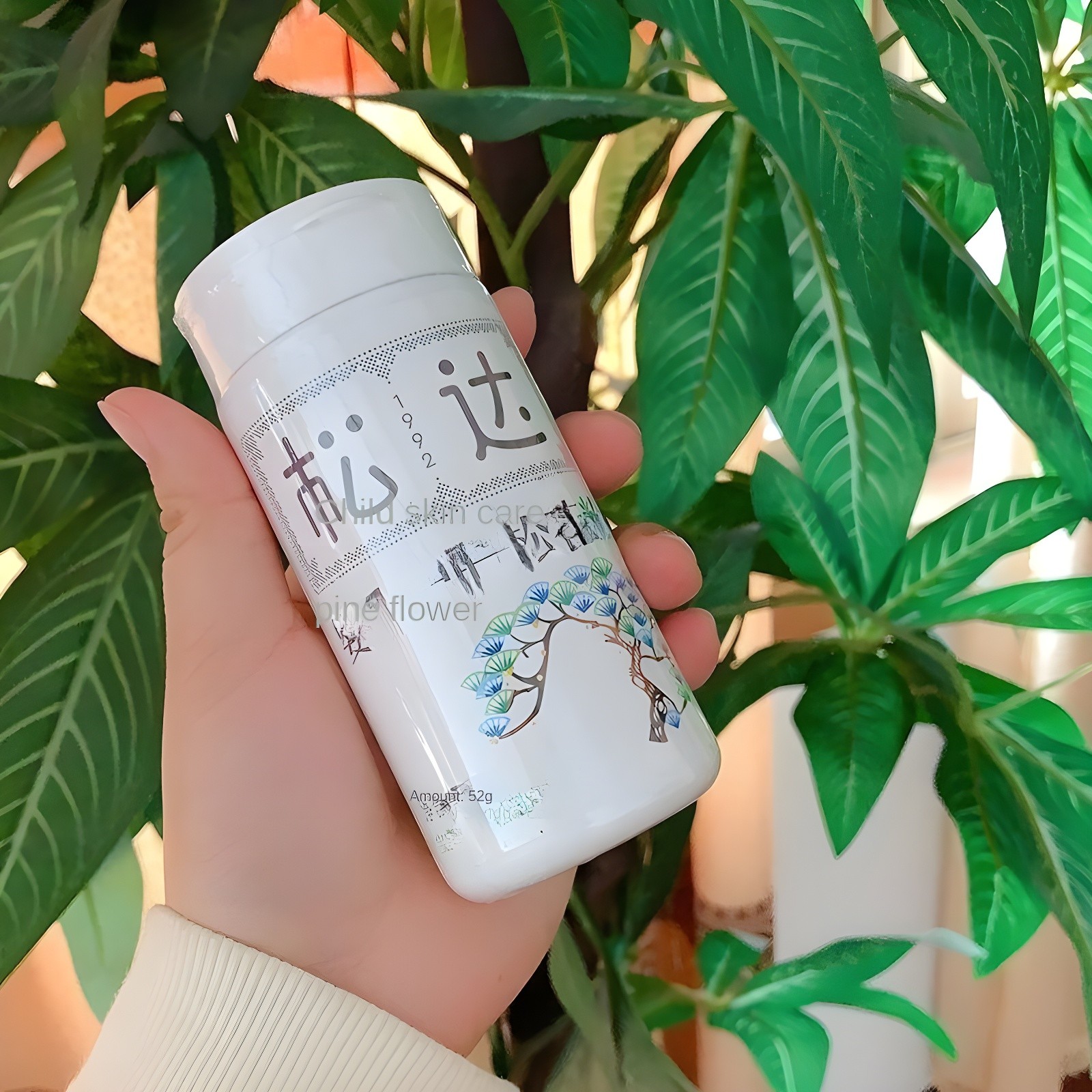 Songda baby talcum powder bottle held in hand against green leaves