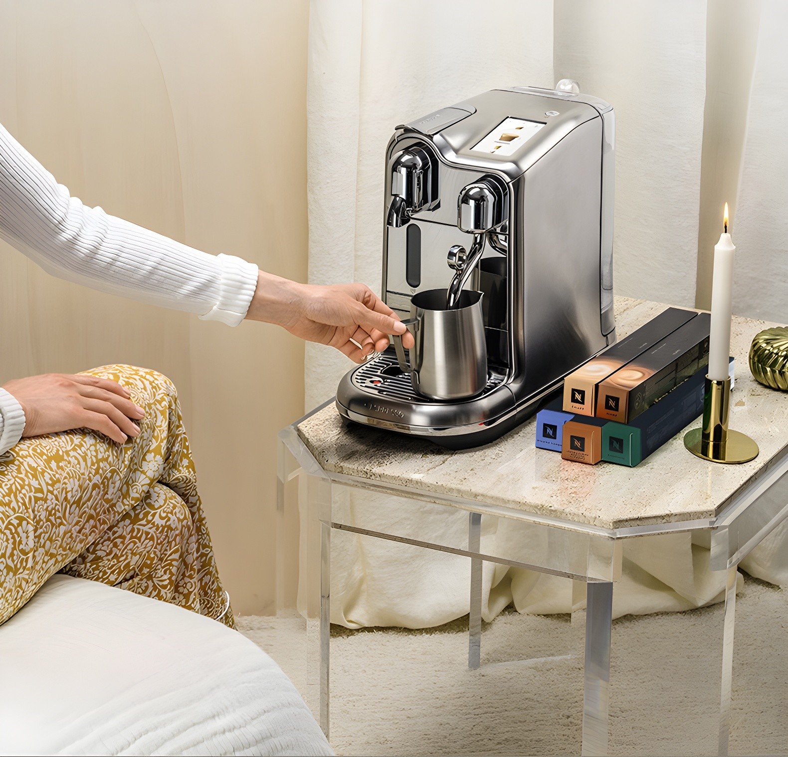 Person using the Nespresso Creatista Pro with milk pitcher and capsule boxes nearby