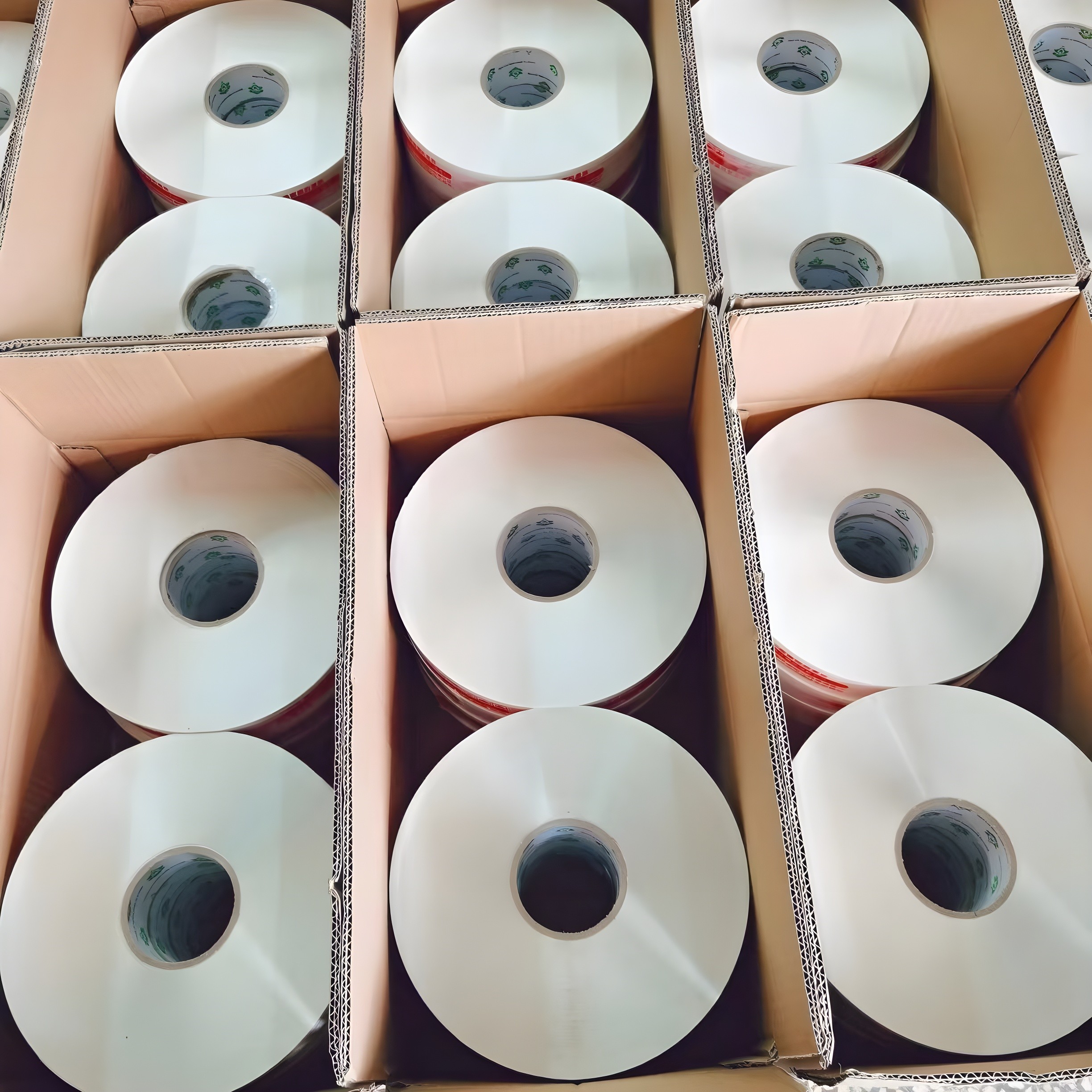 Top-down view of multiple jumbo tape rolls packed in cardboard boxes, showcasing bulk industrial supply