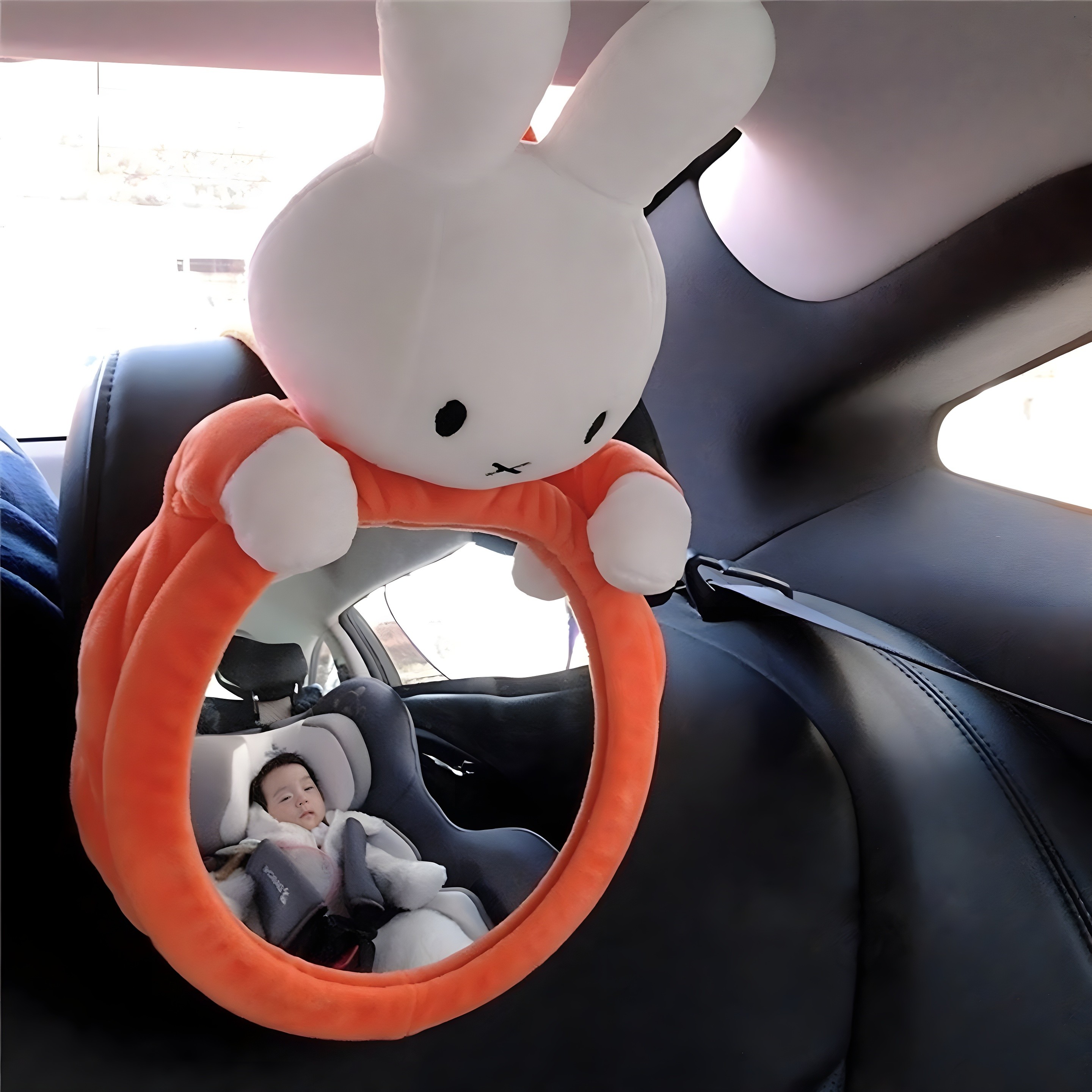 Miffy (white rabbit) baby car mirror installed in a car, reflecting a child in a car seat