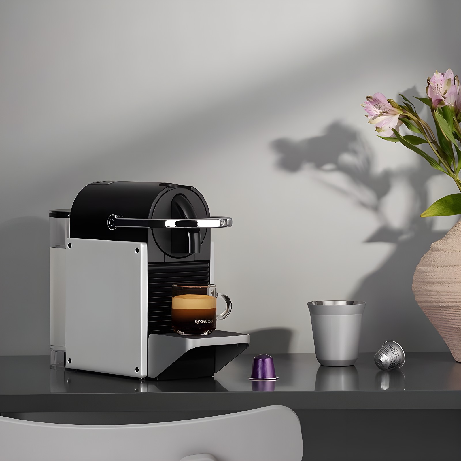 Nespresso Pixie in silver on dark countertop with purple capsule and silver cup