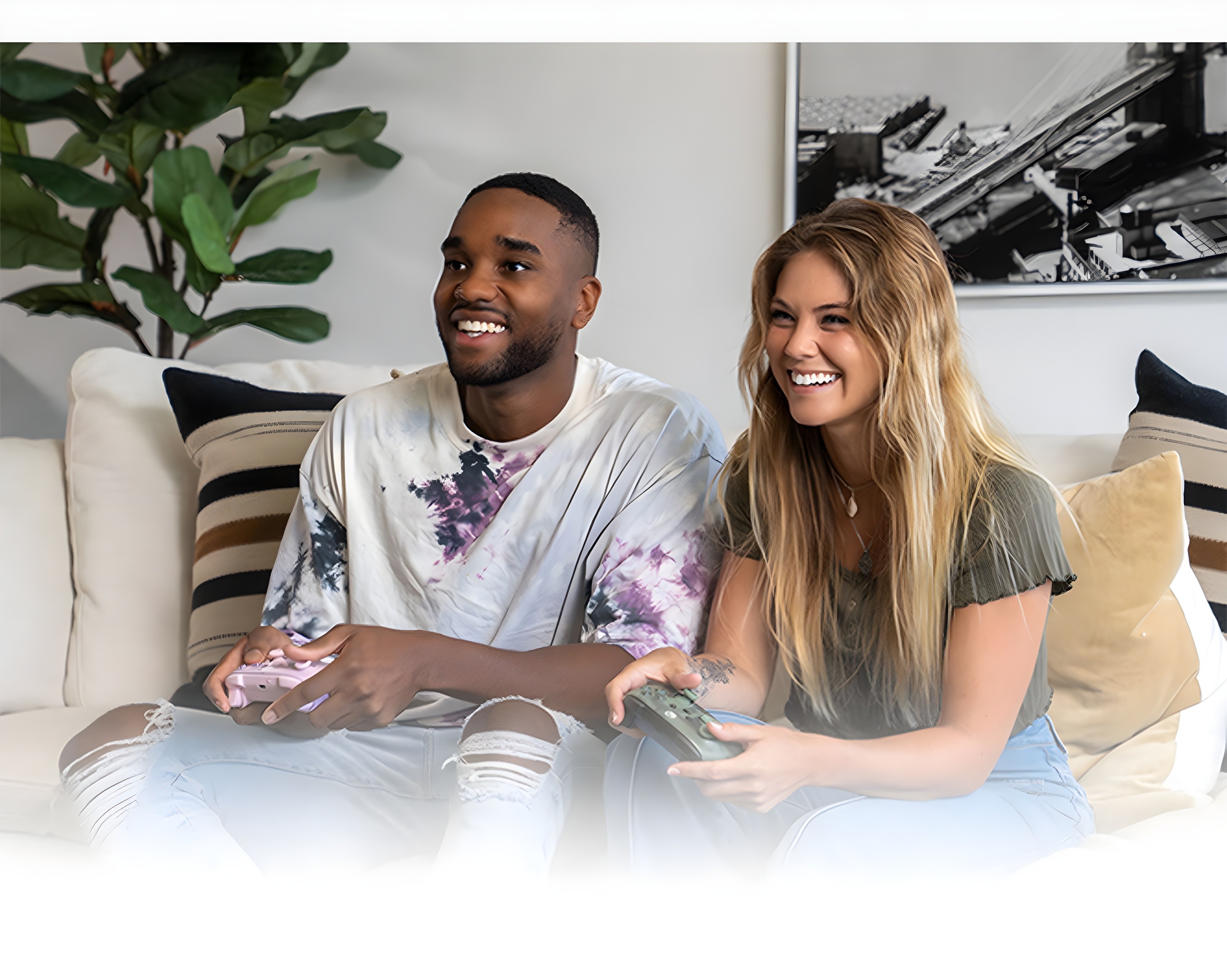 Two friends smiling while playing games together on a couch